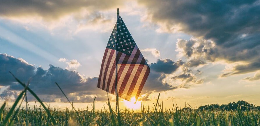 Photo of an American flag in a field representing how veterans of the armed forces may have untreated PTSD. However, it's important to note that many people who haven't served also developed PTSD from traumatic experiences.