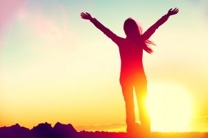 A woman stands with her arms outstretched in celebration as the sun rises. This could symbolize the joy of overcoming trauma after EMDR trauma therapy in St. Petersburg, FL. An online EMDR therapist in Tampa, FL can help you overcome your trauma. Reach out today! 