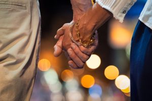A close up of a couple holding hands with blurred lights in the background. This could symbolize the stronger bonds that couples therapy in Tampa, FL can help cultivate. A couples therapist in Saint Petersburg, FL can help couples on the brink in Florida. Learn more about couples therapy in marriage counseling in Tampa, FL! 33609 | 33704 | 33703 