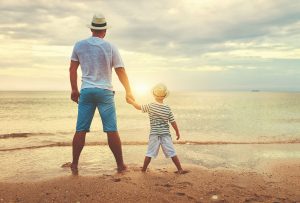 A father holds the hand of their child while standing on a shore. Learn more about the support PCIT in St. Petersburg can offer by seraching "PCIT therapy near me" or contacting a PCIT therapist in Tampa, FL today.