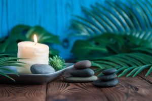 Lit candle and smooth stacked rocks representing a calm atmosphere for a clinical interview. Complete your Psychoeducational Testing in South Tampa, Florida with Wellness Psychological 