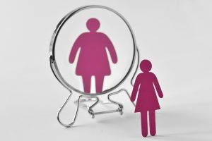 A paper cutout of a woman sees a distorted view of themselves. Contact an eating disorder therapist in St. Pete, FL to learn more about eating disorder treatment in Tampa, FL and the support online eating disorder therapy in Tampa, FL can offer. 