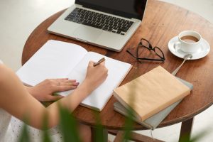 A person writes in a journal while sitting at a round desk. Contact a therapist in Tampa, FL to learn more about psychological testing in Tampa, FL and the support psychoeducational testing near me can offer today. Or, learn about other Florida counseling and evaluation services offered. 