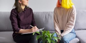 A woman smiles while flipping through their clipboard across from a girl. Learn how a therapist in Tampa FL can offer support with mental health. Contact a therapist in St. Pete, FL to learn more about online therapy in Florida and other services. 