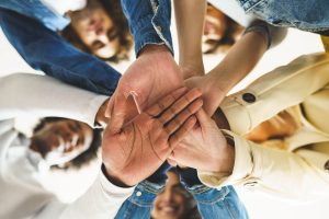A close up of people putting their hands in a pile while smiling at the camera. This symbolizes the unity and support a community can offer via group therapy in Tampa, FL. Learn more about men’s group therapy in Tampa, FL, and other services like a grief support group in Tampa, FL today