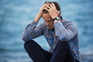 a middle aged man sitting down with his hands in his hair as he is feeling stressed, anxiety specialist, anxiety therapy in tampa 